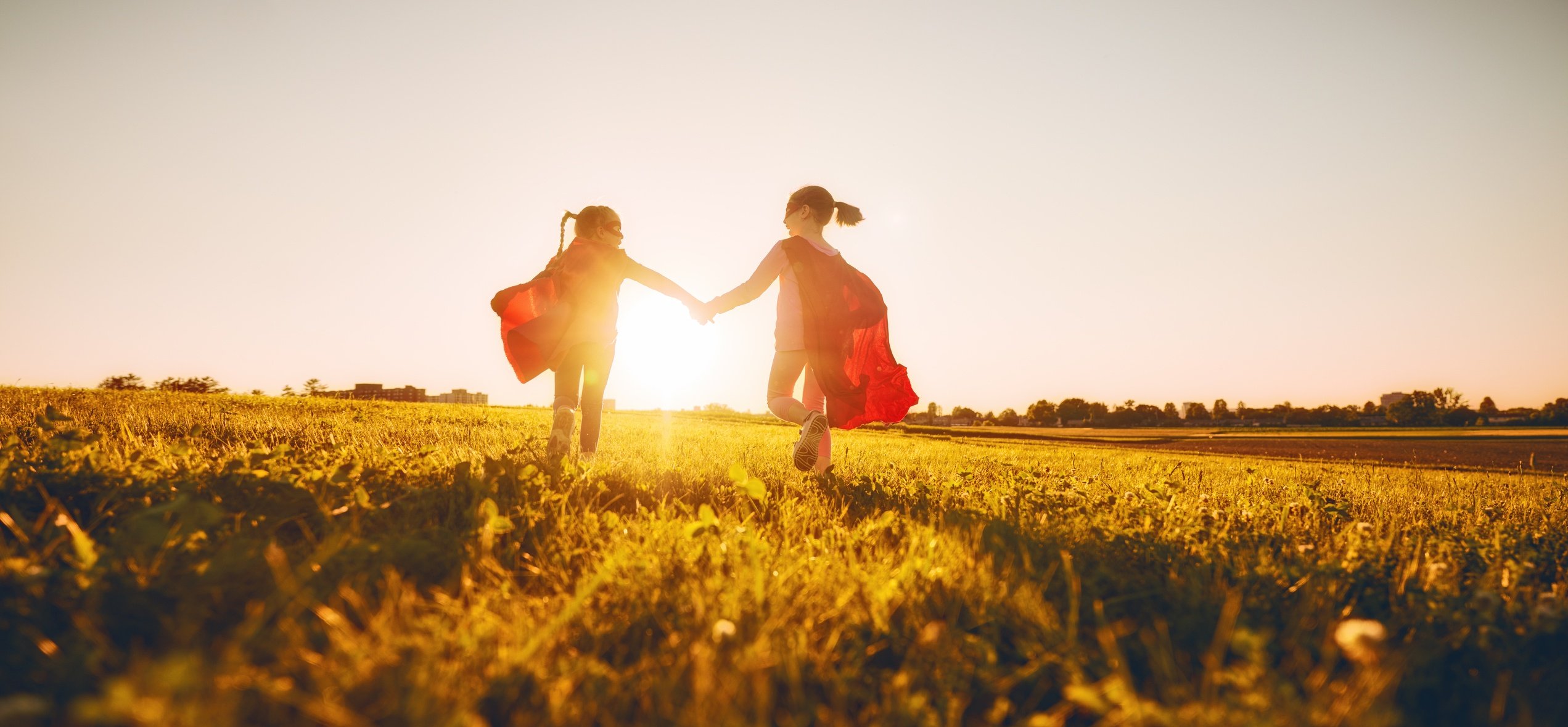 Children Dressed as Superheroes Running Through a Field